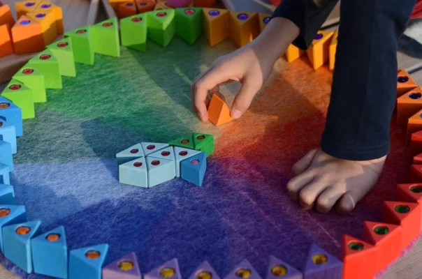 Kind speelt op Bauspiel Regenboog Kleed van wolvilt